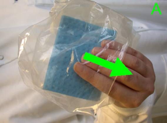 An operative holding a sponge swab through the sterile plastic sample bag. An arrow points over the operative's hand to demonstrate how the bag is folded back to expose the sterile sponge without contaminating it 