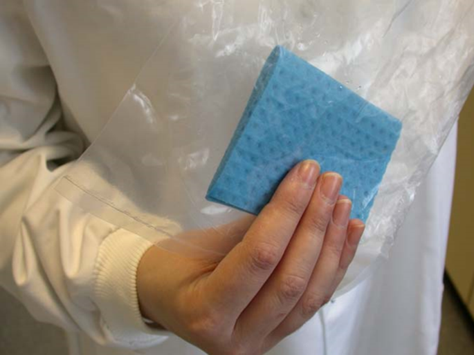 An operative holding a sponge swab through the sterile plastic sample bag 