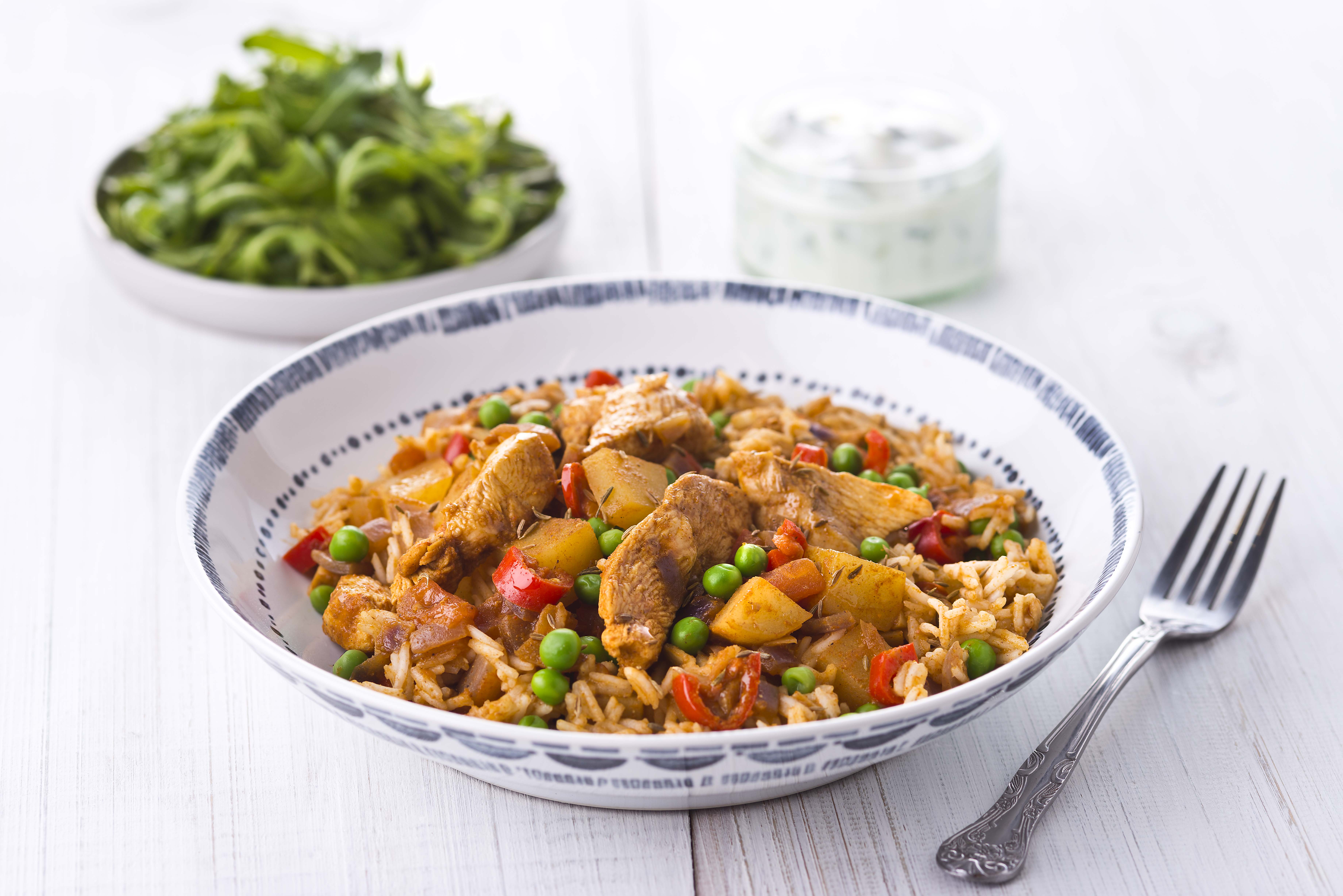 A serving of Chicken Biryani with rice and green beans on the side