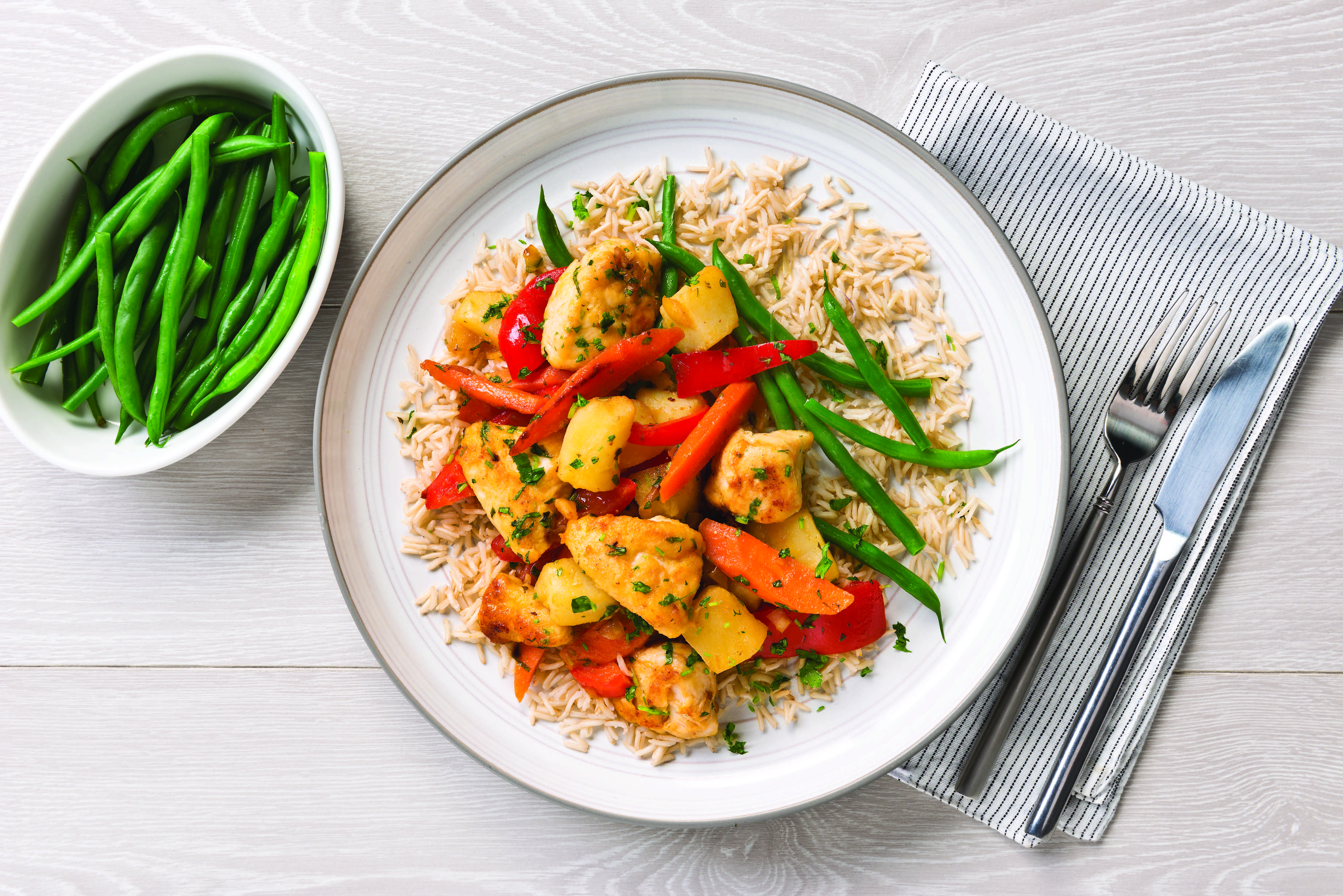 A serving of citrus chicken with rice and green beans