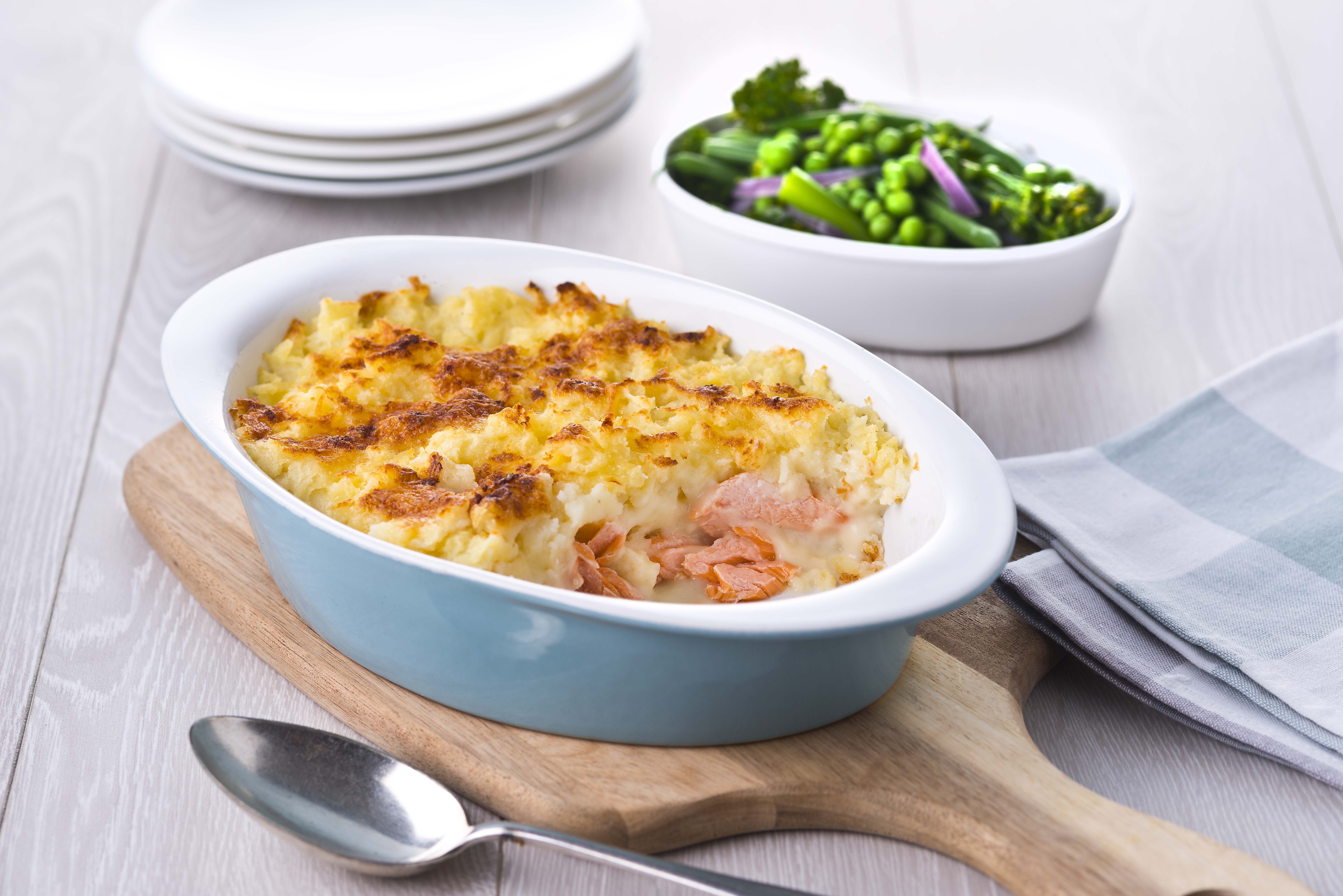 A serving of fish pie with a side dish of peas