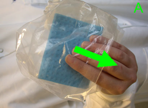 An operative holding a sponge swab through the sterile plastic sample bag. An arrow points over the operative's hand to demonstrate how the bag is folded back to expose the sterile sponge without contaminating it