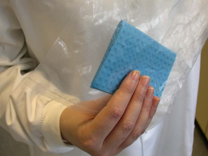 An operative holding a sponge swab through the sterile plastic sample bag