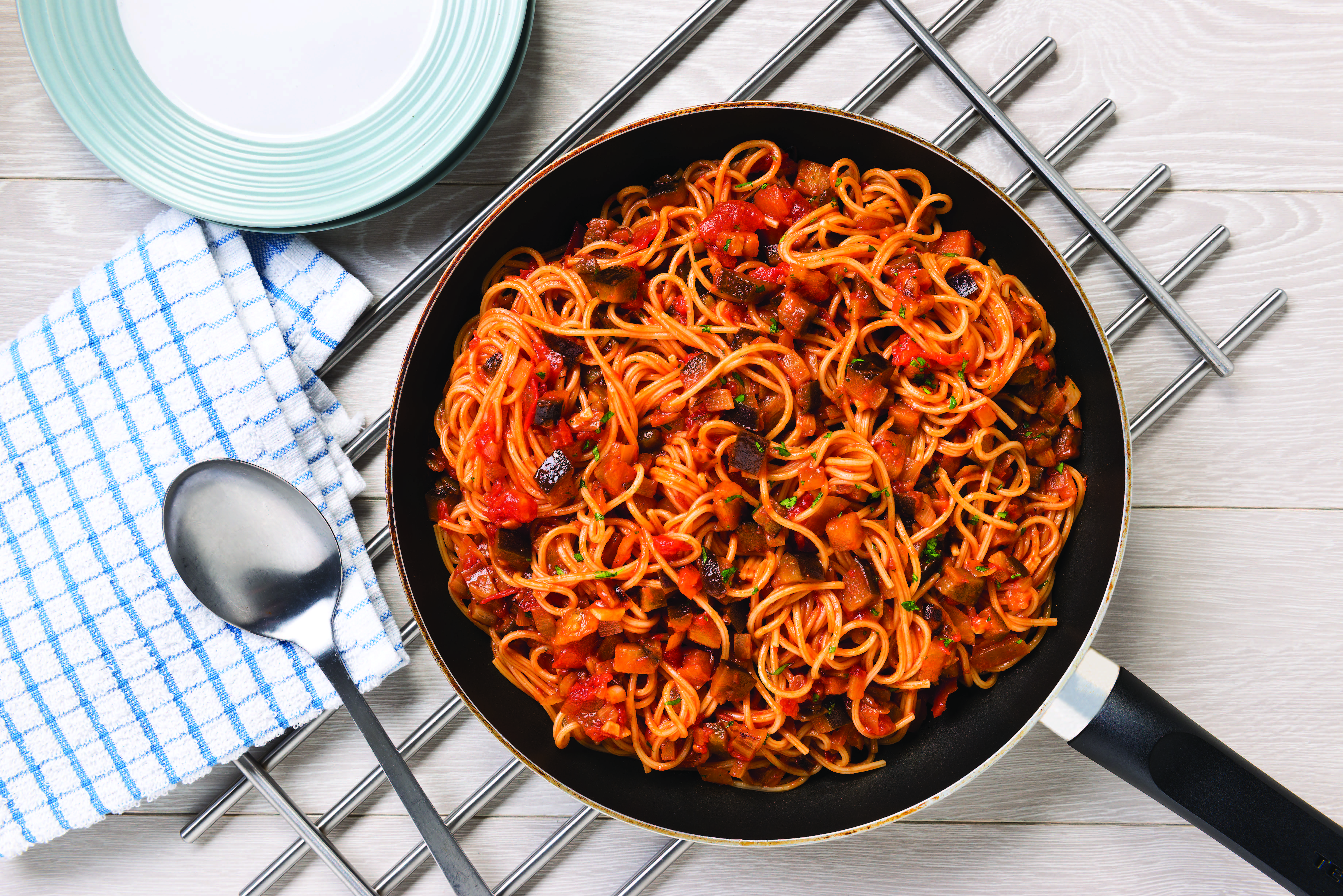 A pan of spaghetti with aubergines on a table