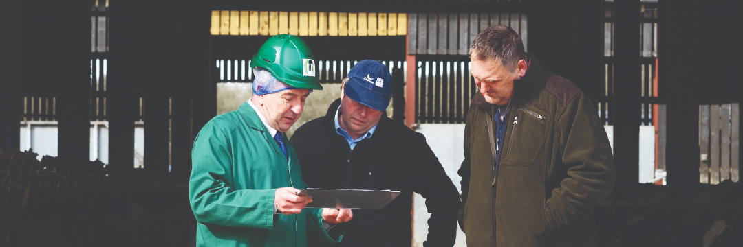 Three people looking at a clipboard on a farm